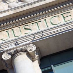 The word Justice on a Courtroom Building.